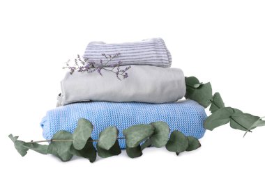 Beyaz arka planda bebek kıyafetleri ve okaliptüs dalları yığını