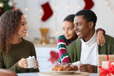 Mutlu Afro-Amerikan ailesi Noel arifesinde evde lezzetli sıcak çikolata içiyor.