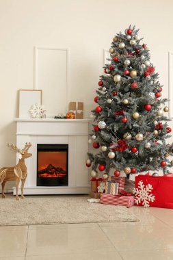 İçinde şömine, Noel ağacı ve ahşap ren geyiği olan aydınlık oturma odası.