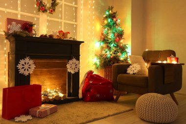 İçinde şömine, Noel ağacı ve parıldayan ışıklar olan oturma odası.