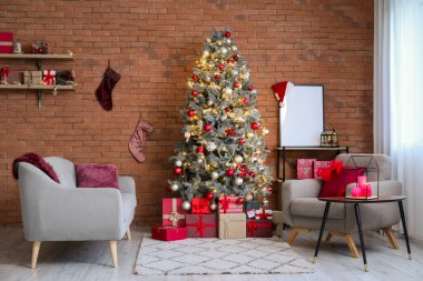 Modern oturma odasının içinde koltuklar ve tuğla duvarın yanındaki Noel ağacı.