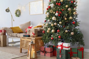 Noel ağacı, hediye kutuları ve ışık duvarının yanındaki kanepe.