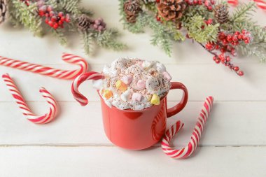 Bir fincan lezzetli kakao, marşmelov ve beyaz ahşap arka planda şeker kamışı.