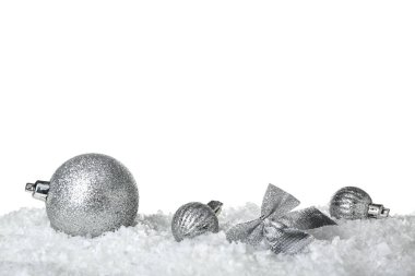 Beyaz arka planda kar üzerine gümüş Noel süslemeleri