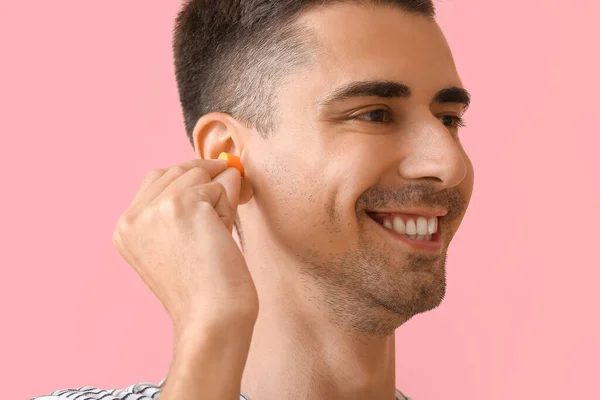 Young Man Putting Ear Plug Pink Background Closeup — Stock Photo, Image