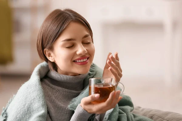 漂亮的年轻女子在家里喝着美味的茶 — 图库照片