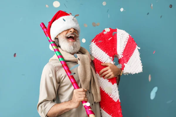 Glücklicher Älterer Herr Mit Weihnachtsmütze Und Zuckerstange Pinata Auf Farbigem — Stockfoto