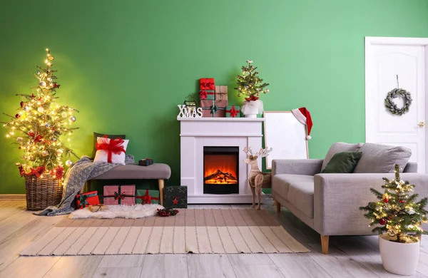 Gri kanepesi, şöminesi ve Noel ağaçları olan şık bir oturma odası.