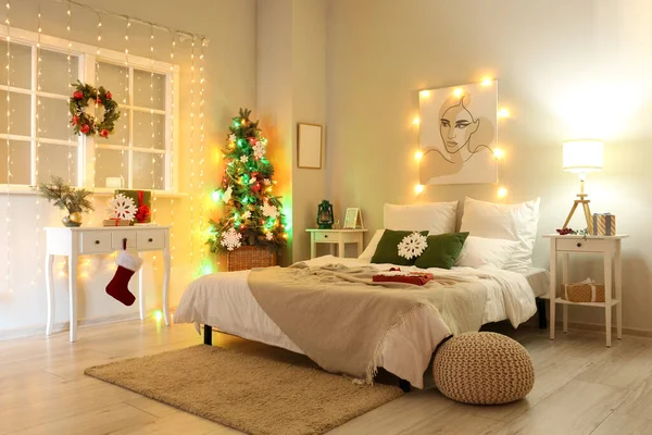 Modern yatak odasının içinde Noel ağacı ve parlayan ışıklar var.