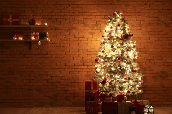 Gyönyörű Karácsonyfa Világító Fények Ajándékdobozok Közelében Téglafal Sötét Szobában — Stock Fotó