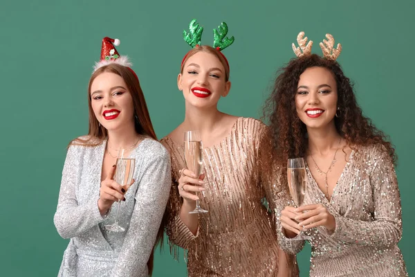 クリスマスの装飾と色の背景にシャンパンのガラスを持つ美しい若い女性 — ストック写真