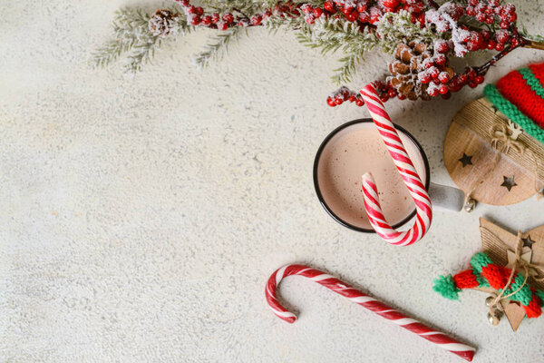 Cup of tasty cacao with candy canes on light background