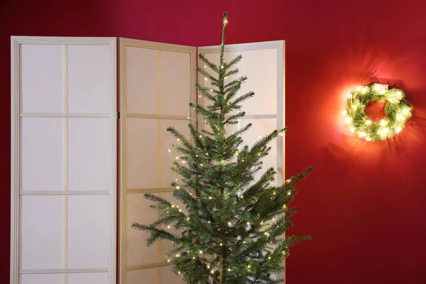Όμορφο Χριστουγεννιάτικο Δέντρο Και Πτυσσόμενη Οθόνη Κοντά Στον Κόκκινο Τοίχο — Φωτογραφία Αρχείου