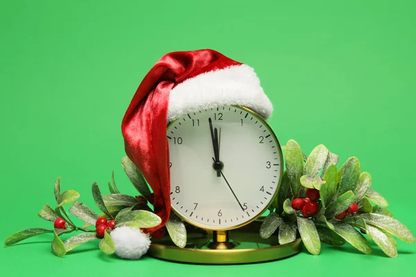 Wecker Mit Weihnachtsmütze Und Dekor Auf Grünem Hintergrund — Stockfoto