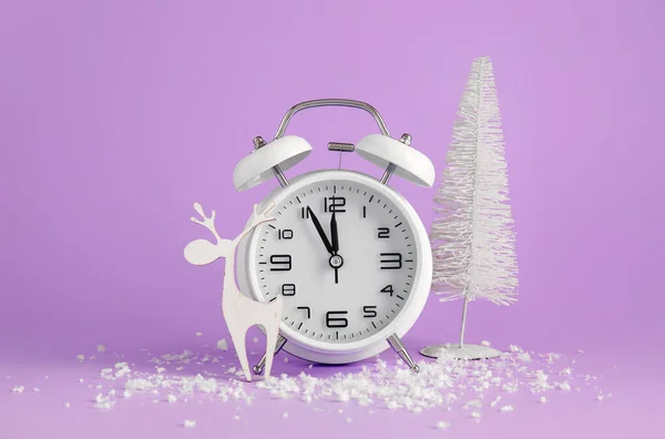 Alarm clock, Christmas decorations and snow on color background