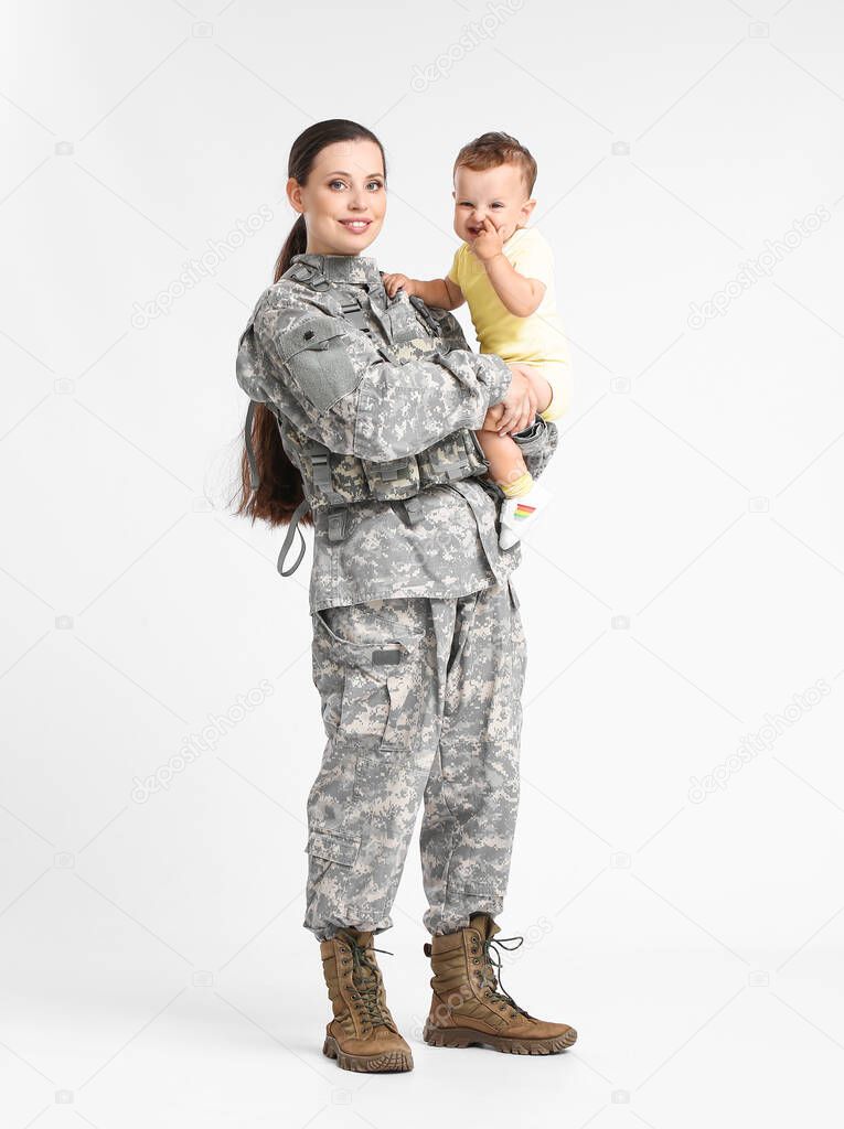 Female soldier with her little son on light background