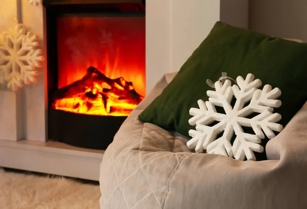 リビングルームで暖炉の近くに大きな雪のフレークと枕を持つバッグチェア — ストック写真