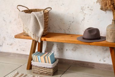 Tahta tezgah, sepetler, şapka ve vazo, ışık duvarının yanında.