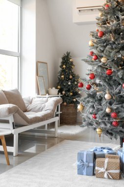 Oturma odasının içinde Noel ağaçları ve hediyeler var.