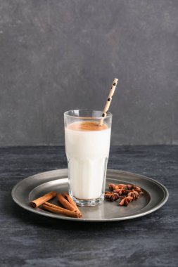 Siyah arka planda tarçınlı bir bardak lezzetli içecek.