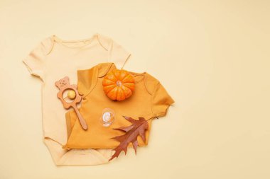 Bebek kıyafetleri, emzik, oyuncak ve balkabağı.