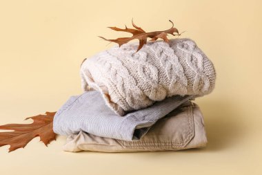 Renkli arka planda bebek kıyafetleri ve sonbahar yaprakları yığını