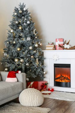 Güzel dekore edilmiş Noel ağacı oturma odasında şöminenin yanında.