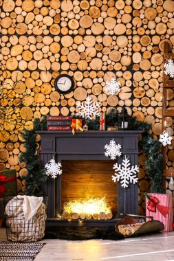 Ahşap duvarın yanında Noel dekorlu şömine.
