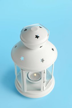 Mavi arka planda yanan mum ile güzel bir Noel feneri.
