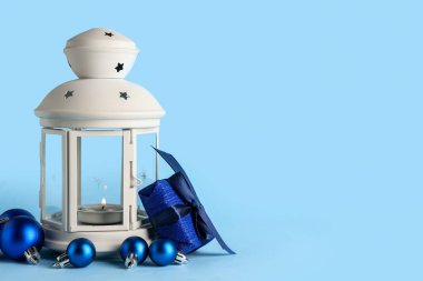 Güzel Noel feneri yanan mum, toplar ve mavi arka planda hediye kutusu