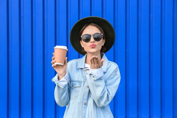 Модная Женщина Держащая Бумажную Чашку Чая Раздувающийся Поцелуй Голубом Фоне — стоковое фото