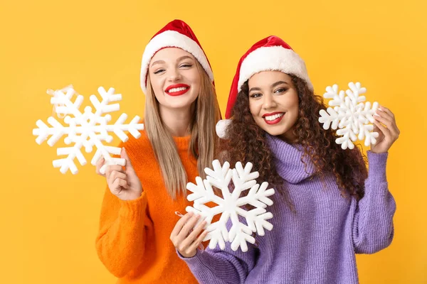 Schöne Junge Frauen Weihnachtsmützen Und Mit Schneeflocken Auf Farbigem Hintergrund — Stockfoto