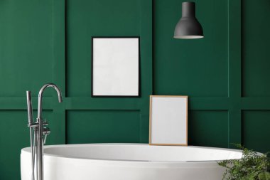 Yeşil duvarın yanındaki boş çerçeveli modern küvet.