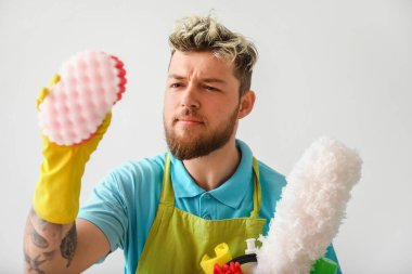 Işık duvarının yanında temizlik malzemesi taşıyan yakışıklı bir genç.