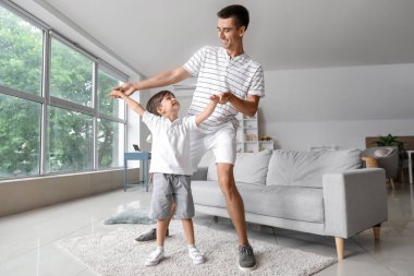 Bir adam ve küçük oğlu evde dans ediyor.