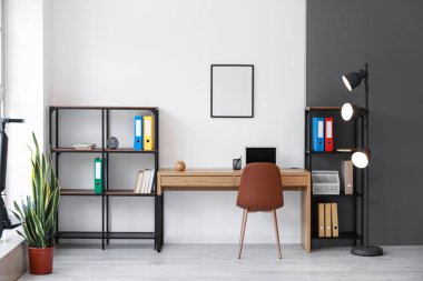 Çalışma yeri, raf üniteleri ve parlayan lambayla aydınlık ofisin içinde.