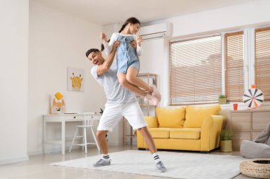 Bir adam ve küçük kızı evde dans ediyor.