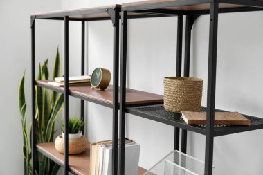 Kitapları, çiçekleri ve ışık duvarının yanındaki organizatörü olan siyah raf ünitesi.