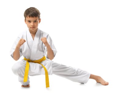 Küçük çocuk beyaz arka planda karate yapıyor.