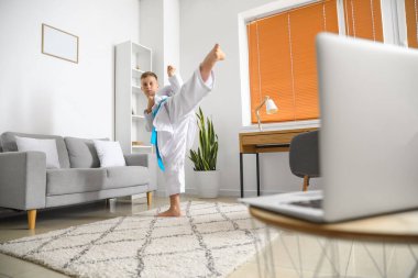 Küçük çocuk evde online karate okuyor.