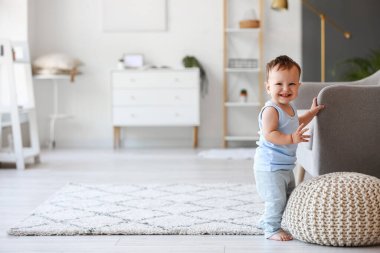 Küçük bebek evde kanepenin yanında yürümeyi öğreniyor.