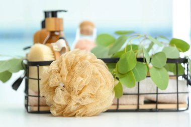 Sünger ve sepet ve banyo malzemeleri masada.