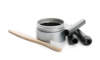 Aktif kömür diş tozu, bambu çubukları ve beyaz arka planda fırçayla dolu kavanoz.