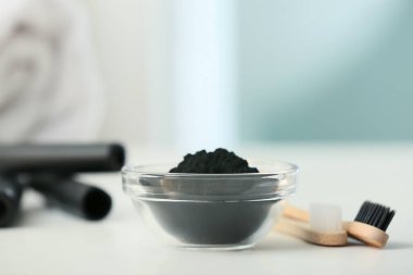 Aktif hale getirilmiş kömür diş tozu ve fırçalarla dolu bir kâse.