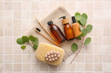 Süngerli banyo malzemeleri ve bej fayansların üzerine ağaç dalları.