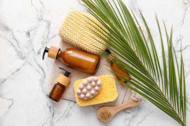 Süngerli banyo malzemeleri ve arka planda palmiye yaprağı.