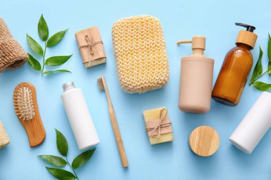 Lif süngerli banyo malzemeleri ve mavi arka planda bitki dalları.