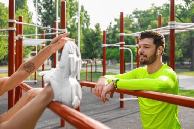 Kulaklıklı genç bir adam ve kız arkadaşı spor sahasında.