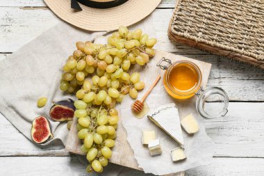 Olgun üzümlü, peynirli ve ballı kompozisyon açık ahşap arka planda