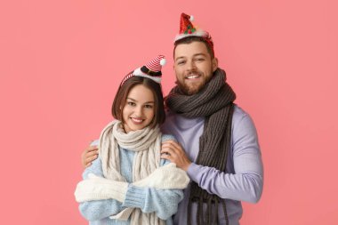 Şık kış kıyafetleri içinde mutlu genç bir çift ve renkli arka planda Noel süslemeleri.